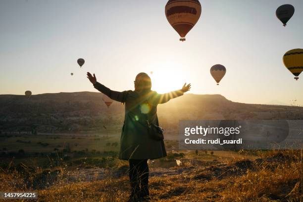 frau genießt den sonnenaufgang mit blick auf den heißen ballon in göreme - hot middle eastern women stock-fotos und bilder