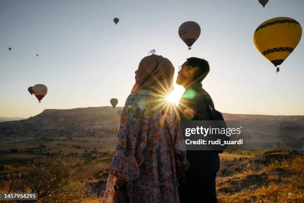 young muslim couple enjoy the sunrise with view of  hot balloon in goreme - turkey middle east stockfoto's en -beelden