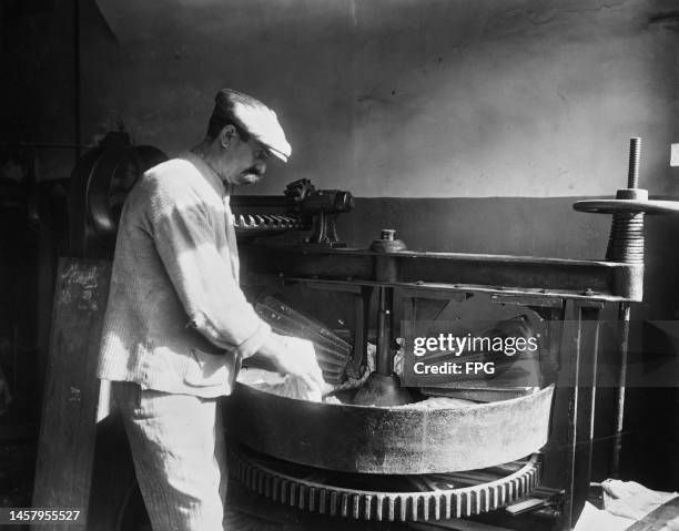 Man working at a stand mixer mixing dough for pasta, at an food production facility, United States, circa 1925.