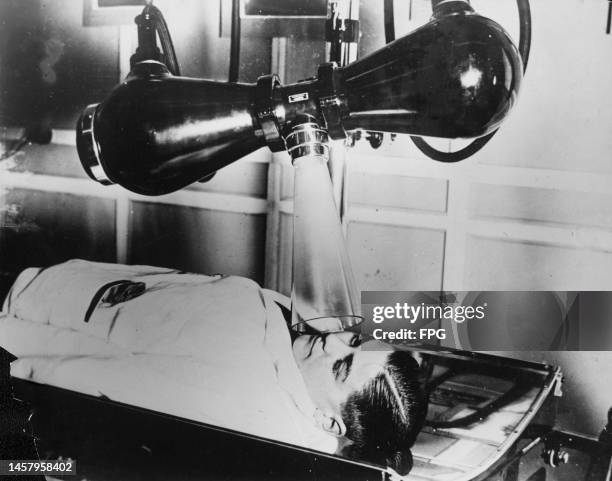 Man lying beneath modern x-ray apparatus during a demonstration at the Exhibition of Radiological Apparatus, during the Congress of the British...