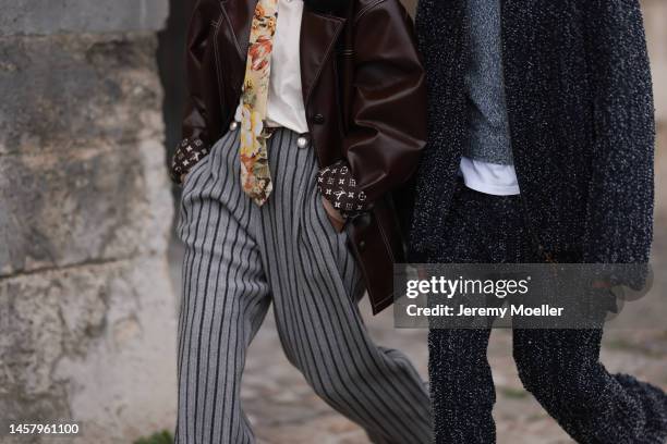 Alice Barbier wears a brown shiny varnished leather coat from Louis Vuitton, a gray and white print pattern LV monogram print pattern denim shoulder...