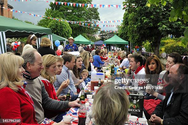 Residents of Melbourne Road, Wimbledon, South West London are seated at a long union-jack bedecked table enjoying food, drink and conversation during...