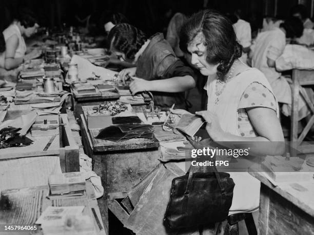 Female gold worker cutting gold leaf which is then placed between the sheets of parchment books in readiness for use, at an workshop in the West End...