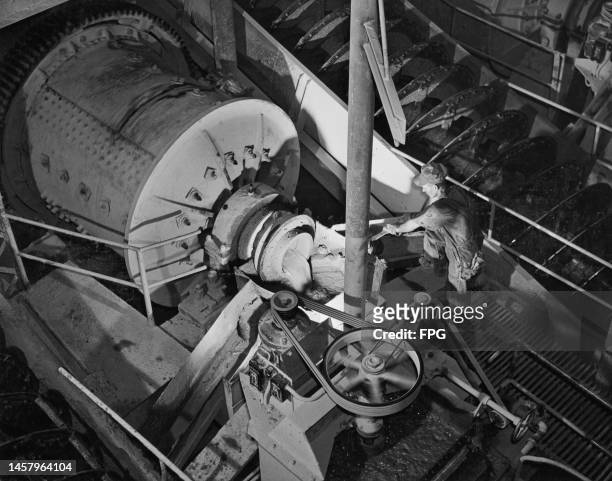 High-angle view of an mine worker inspecting the ball mill, at an Golden Cycle Corporation gold mining and milling operation, United States, circa...