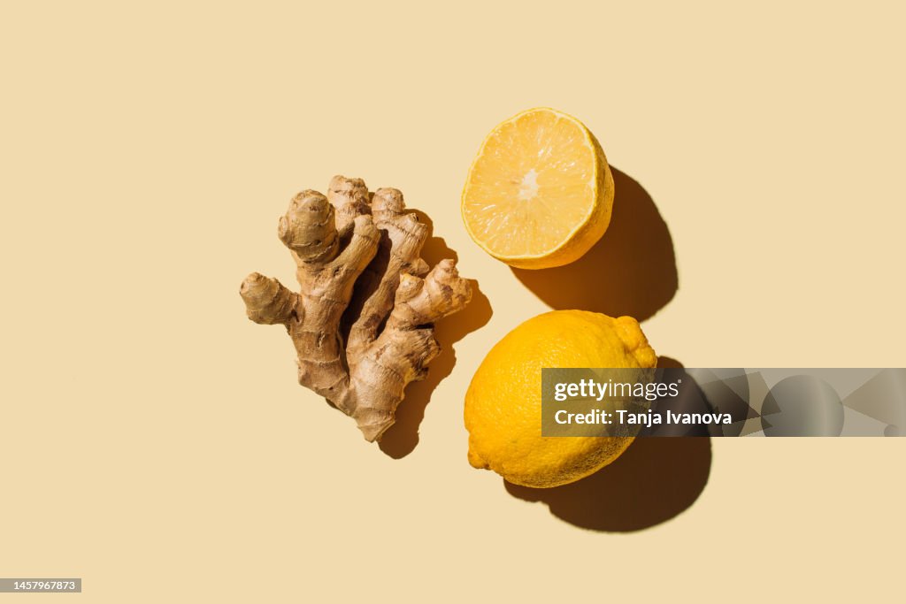 Fresh ginger with lemon on beige background. Flat lay, top view, copy space.