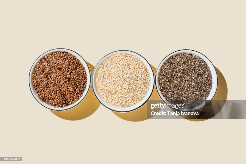 Assortment of seeds, healthy food ingredients, superfood. Flat lay, top view, copy space. Chia, flax seeds, white sesame seeds on beige background.