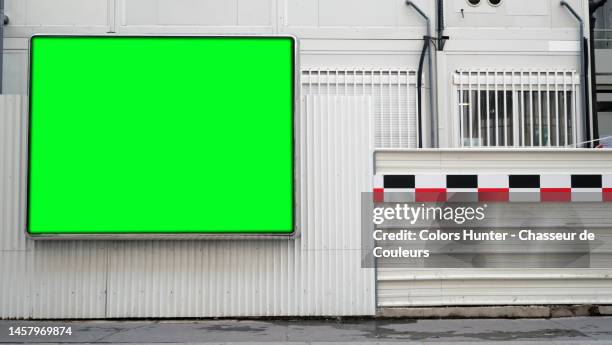 green and empty billboard in front of a building site with sidewalk in paris, france - palissades stockfoto's en -beelden