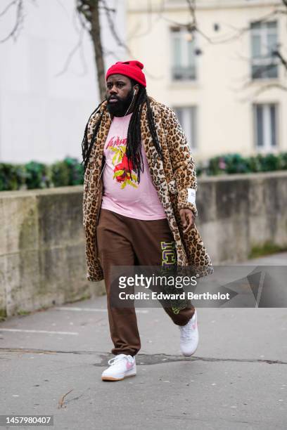 Guest wears a red cut-out wool ribbed beanie, a pale pink with red and yellow print pattern t-shirt, a beige and brown leopard print pattern fluffy...