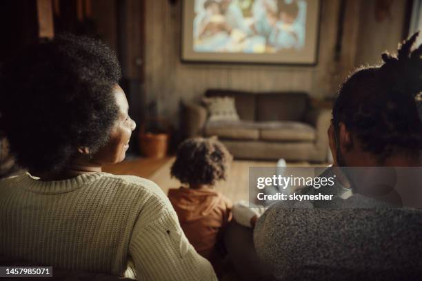 afroamerikanische familie, die einen umzug zu hause beobachtet. - movie and tv fotos stock-fotos und bilder