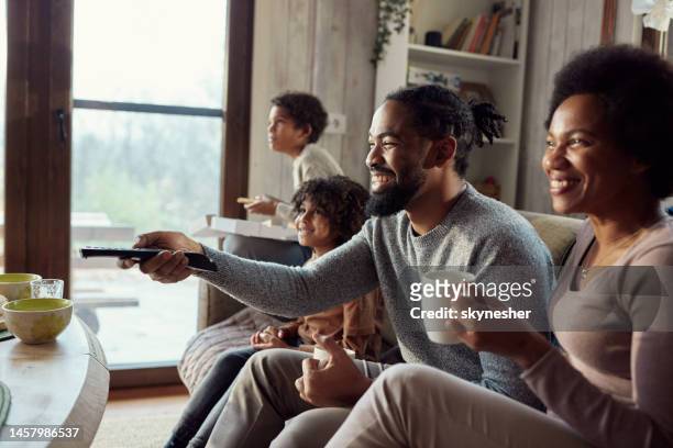 happy black family enjoying while watching tv at home. - african family watching tv stockfoto's en -beelden