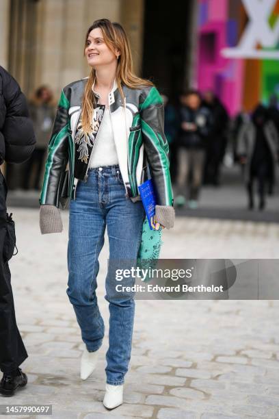 Eugenie Trochu wears a white fluffy t-shirt, a black / white / green grained leather with embroidered silver and gold fire pattern zipper jacket,...