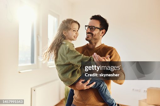Carefree father and daughter dancing at their new apartment.
