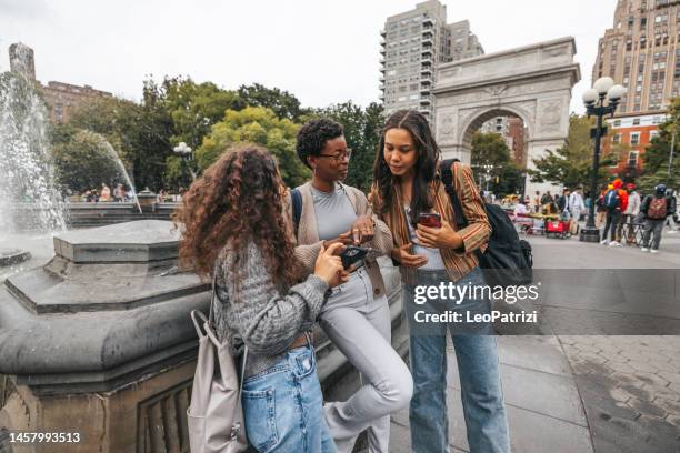 three students at washington square in new york texting on mobile phone - washington square park 個照片及圖片檔