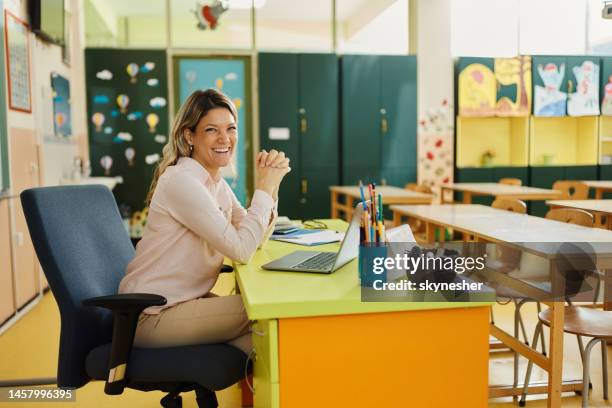 happy female teacher in the classroom. - classroom desk stock pictures, royalty-free photos & images