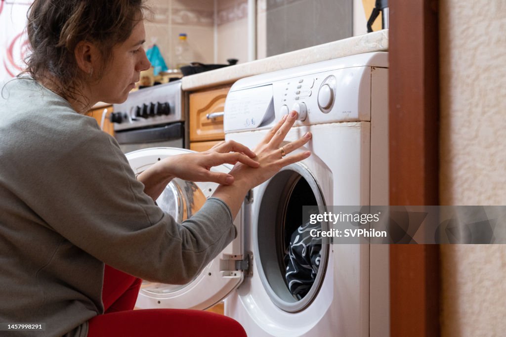 La casalinga graffia la dermatite sulla pelle della sua mano durante le faccende domestiche.