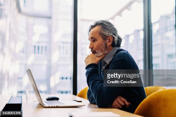 gens d’affaires en poste. homme d’affaires senior utilisant un ordinateur portable dans un bureau d’entreprise moderne - décision photos et images de collection