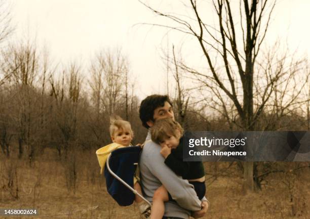 vintage late 1960s photo of young dad carrying kids on a walk in the woods - archival family stock pictures, royalty-free photos & images