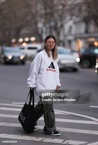 Dani Verdari seen wearing black Adidas gazelle sneaker, white socks, blau / green wide jeans trousers, white oversized sweater, black shoulder bag...