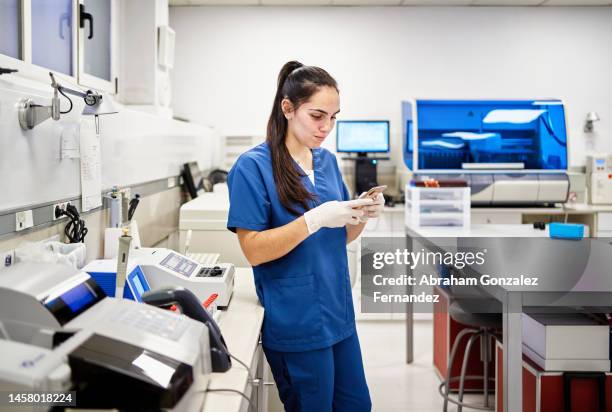 woman using a mobile while working in an analysis laboratory - scientific sample stock pictures, royalty-free photos & images