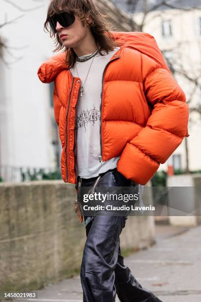 Perto wears an orange puffed jacket, grey Swampgod t-shirt, Swampgod leather pants, outside Rick Owens, during Paris Fashion Week - Menswear...