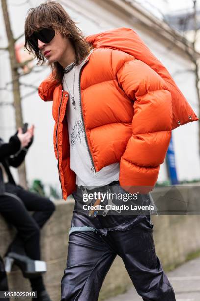 Perto wears an orange puffed jacket, grey Swampgod t-shirt, Swampgod leather pants, outside Rick Owens, during Paris Fashion Week - Menswear...