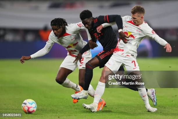 Alphonso Davies of Bayern Munich battles for possession with Mohamed Simakan and Dani Olmo of RB Leipzig during the Bundesliga match between RB...