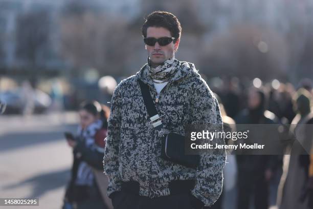 Marc Forne seen wearing a black / white Givenchy jacket, black / white scarf, black shades, black Givenchy shoulder bag and a black trousers before...
