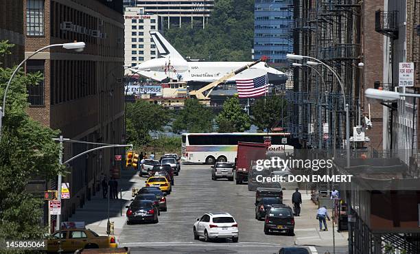 The Space Shuttle Enterprise makes its way up the Hudson River past a busy street as it is towed to the Intrepid Museum on a barge June 6, 2012 in...
