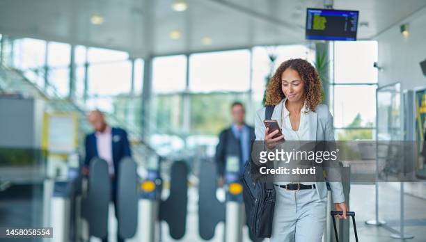 geschäftsreisende, die ihre nachrichten bei der ankunft überprüfen - business woman on phone stock-fotos und bilder