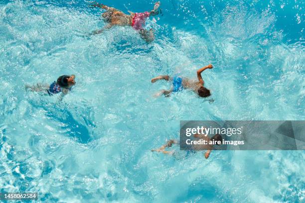 aerial view of a group of children swimming in a blue pool having fun on a sunny day - pond 個照片及圖片檔