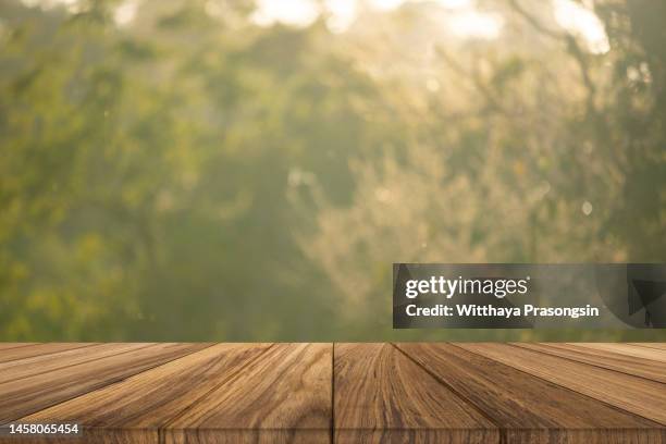 empty wooden table with defocused green lush foliage at background - picnic table stock-fotos und bilder