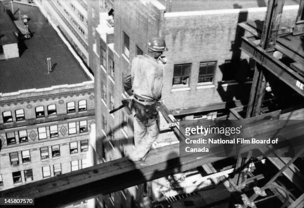 Steel worker is at work, high above street level, on the construction of a skyscraper , New York, New York, 1964. Photo taken during the National...