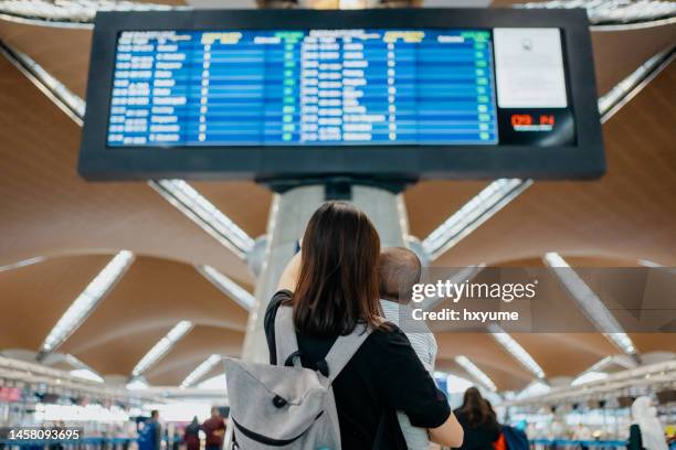 mother and baby looking at arrival departure board in airport - kuala lumpur airport stock pictures, royalty-free photos & images