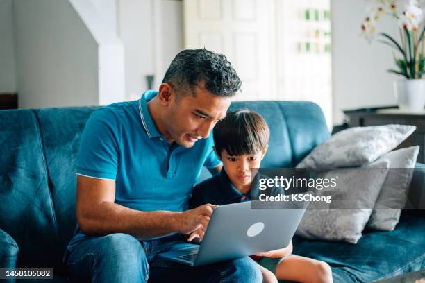 father using the laptop with son at home - malayan ethnicity stock pictures, royalty-free photos & images