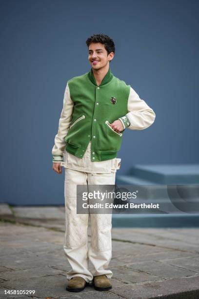 Manu Rios wears gold earrings, a green felt wool with white leather sleeves with embroidered logo teddy cap from Dior, a white latte denim shirt from...