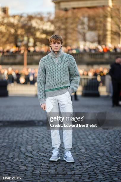 Guest wears a gray and green cut-out pattern / zipper high neck pullover, white pants, gray matte leather ankle sneakers from Dior, outside Dior,...