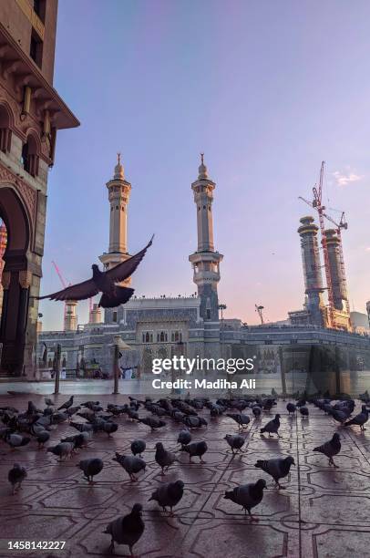 minarets of masjid al haram where pilgrims do tawaaf of khaana kaaba in holy mosque of al haram for hajj and umrah | motion of people wearing ihram for haj and umra, mecca, saudi arabia - mawlid foto e immagini stock