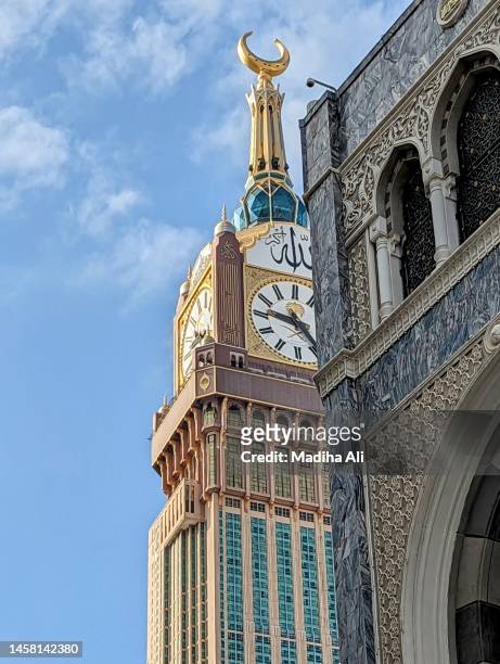clock or mecca / makkah tower near khaana kaaba in holy mosque of al haram while pilgrims doing tawaaf  of kaba for hajj and umrah | motion of people wearing ihram for haj and umra, mecca, saudi arabia |  highest building architecture - makkah clock tower stock-fotos und bilder
