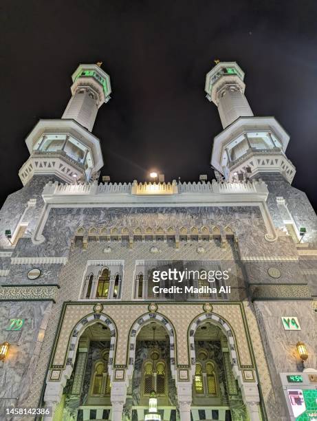 minarets of masjid al haram where pilgrims do tawaaf of khaana kaaba in holy mosque of al haram for hajj and umrah | motion of people wearing ihram for haj and umra, mecca, saudi arabia - masjid al haram stock pictures, royalty-free photos & images