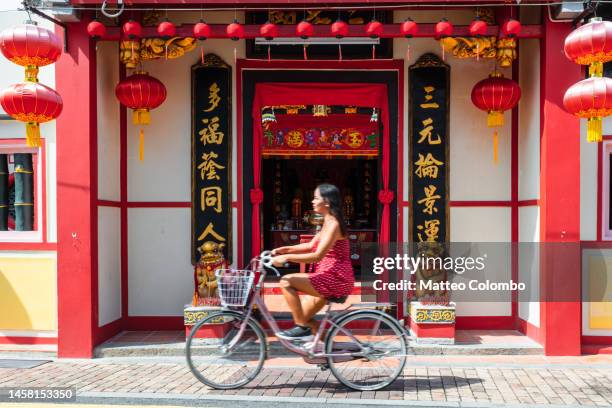 asian tourist on a bicycle near temple, malacca, malaysia - chinese script stock pictures, royalty-free photos & images