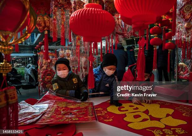 Children wear masks as they look at a large banner with the character Fu or luck as they shop for decorations for the Chinese Lunar New Year and...