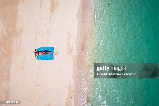 overhead view of young asian woman sunbathing at the beach - aerial view photos fotografías e imágenes de stock