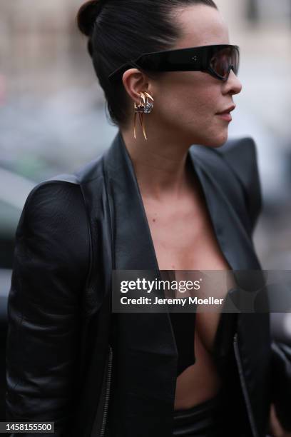 Fashion week guest seen wearing a matching black leather look with a leather jacket and a leather dress with a wide cutout, dark oversized shades and...