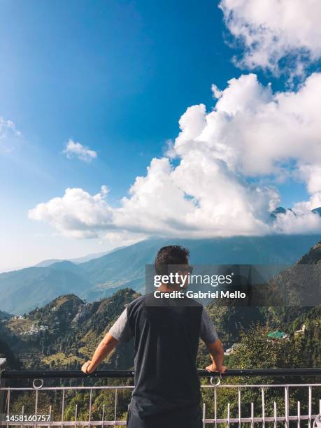 man standing in a balcony staring the views over the mountains - dharamsala stock pictures, royalty-free photos & images