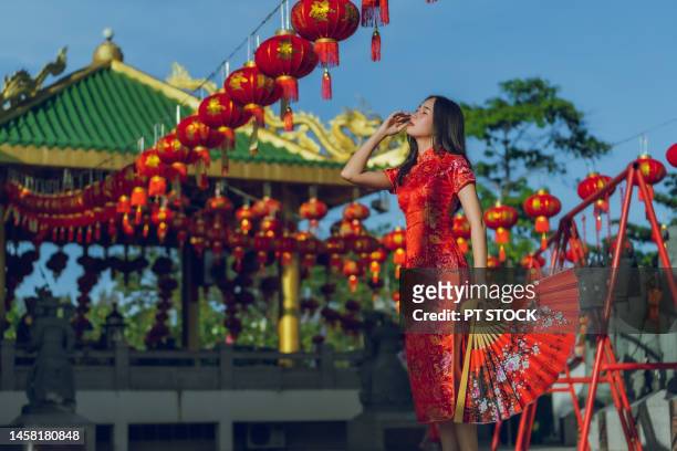 a woman wearing a cheongsam and holding a red fan on chinese new year, there are many red lanterns. - the cheongsam stock-fotos und bilder