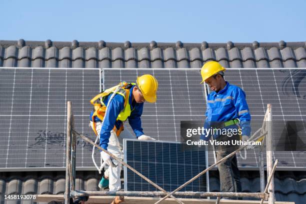 professional worker installs solar panels on the roof of a energy efficient green home. - property developer stock pictures, royalty-free photos & images