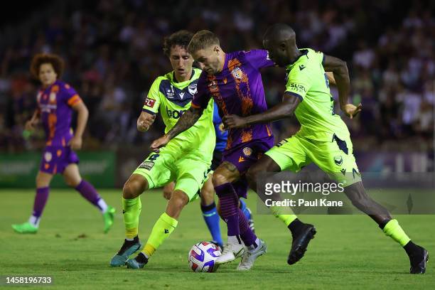Adam Taggart of the Glory contests for the ball against Jay Barnett and Jason Geria of the Victory during the round 13 A-League Men's match between...