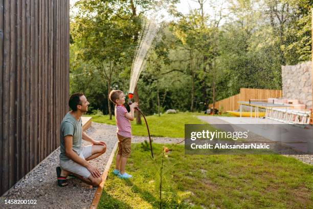 watering the lawn together - garden hose imagens e fotografias de stock