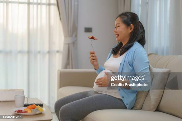 beautiful asian pregnant woman happily eat fruit, organic healthy food, in a cozy home living room. - water apples stock pictures, royalty-free photos & images