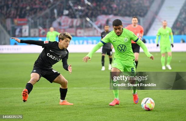 Paulo Otavio of VfL Wolfsburg runs with the ball whilst under pressure from Ritsu Doan of SC Freiburg during the Bundesliga match between VfL...